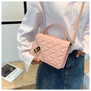 Detail of pink quilted small square bag with gold metal chain and refined hardware
