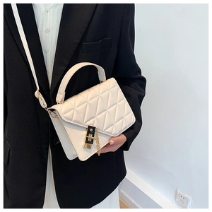Detailed view of beige quilted handbag with elegant gold clasp and chain on black blazer