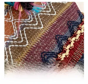 Close-up of colorful ethnic embroidery patterns and fringe details on the woven tote bag