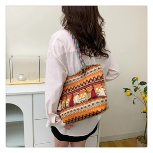 Close-up of bohemian woven tote bag with ethnic geometric patterns and tassel details