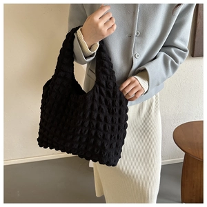 Fashionable black bubble texture hobo bag worn by a model in a casual clear setting
