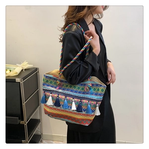 Close-up of ethnic woven tote bag with colorful geometric patterns and long blue tassels