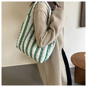 Détail de la texture gaufrée à rayures vertes et blanches sur un grand sac cabas d'épaule