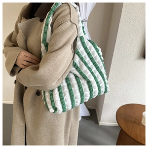 Detailed view of a green and white striped bubble tote bag on a model trench coat