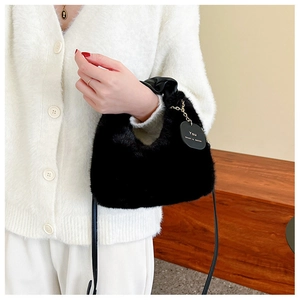Détail du sac à main en fausse fourrure noire avec étiquette en cuir et chaîne dorée