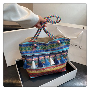 Detailed close-up of woven ethnic pattern tote bag with colorful tassel fringe