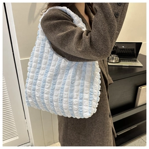 Détail de la texture gaufrée rayée bleu et blanc sur un grand sac cabas à l'épaule