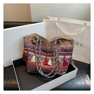 Detail of bohemian knit tote bag showing colorful geometric patterns and fringe charms
