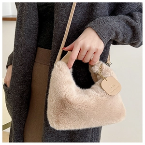 Gros plan d'un sac à main en peluche abricot avec fourrure douce et étiquette en cuir