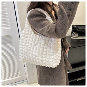Close-up of a white puffer cloud tote bag with textured bubble design worn by a model