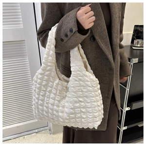 Gros plan du sac fourre-tout blanc texturé à bulles porté par un mannequin en blazer