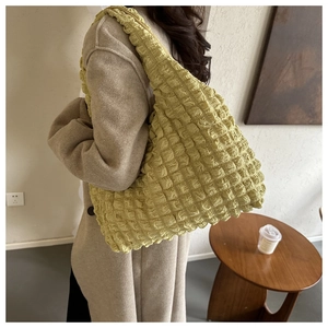 Gros plan du sac bandoulière vert clair à texture popcorn porté par un mannequin
