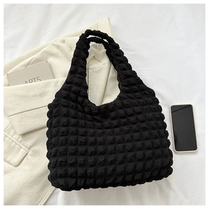 Close-up of black bubble textured fabric on a large tote bag with lifestyle accessories