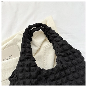 Vue détaillée d'un sac cabas noir à texture gaufrée bulle avec bandoulière bouffante