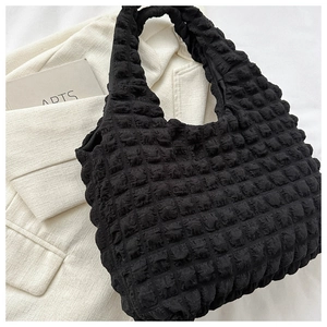 Detail of the black puffy cloud bag with bubble texture on a white blazer background