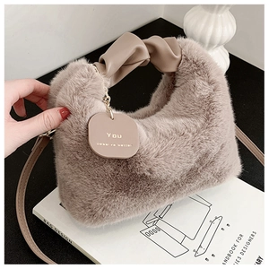 Détail du sac à main en peluche avec poignée en cuir et étiquette dorée