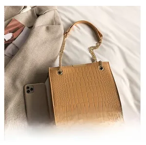 Close-up of brown crocodile pattern shoulder bag with gold chain and metal trim details