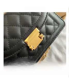 Macro detail of golden metal lock and quilted embroidery on black leather crossbody bag