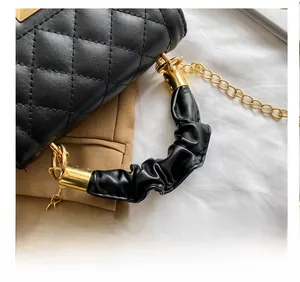 Detail of black quilted leather bag featuring a ruched handle and gold metal hardware
