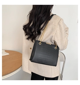 Close-up of black crocodile pattern faux leather tote bag with elegant gold chain strap