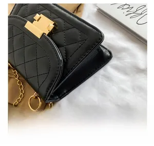 Close-up of black quilted faux leather crossbody bag with gold chain and square buckle