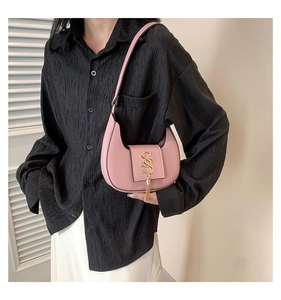 Detail of pink half-moon hobo bag with a gold S-shaped logo and metallic tassel charm