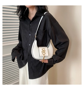 Close-up of a white half-moon shoulder bag with a gold S logo and fringe detail