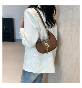 Detailed view of a brown leather crescent shoulder bag with golden logo and tassel