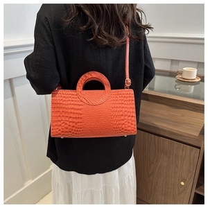 Detailed view of crocodile pattern handbag with hollow handle in bright orange leather