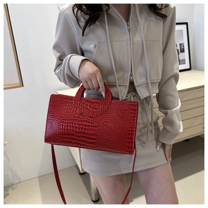 Detail of red crocodile pattern handbag with hollow handle and adjustable shoulder strap