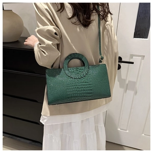Detailed close-up of dark green faux leather handbag featuring a refined crocodile texture