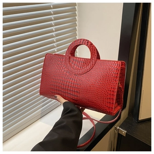 Detail of red crocodile texture handbag with circular handle and detachable strap