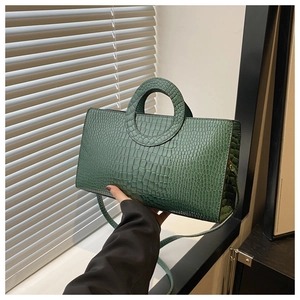 Detail of emerald green crocodile embossed texture and round handle on luxury handbag