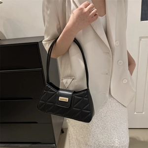 Bolso de hombro acolchado negro con cierre dorado lucido por una modelo elegante