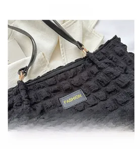 Close-up of black bubble textured tote bag with FASHION leather tag and gold ring