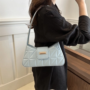 Bolso baguette acolchado azul claro con cierre dorado llevado por una modelo