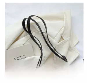 Detail of black pleated tote bag showing premium leather handle and gold hardware ring