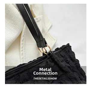 Detail showing the black bubble texture fabric and golden metal ring strap connection