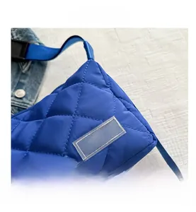Close-up of royal blue quilted tote bag featuring a PVC fashion label and plastic buckle