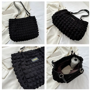 Macro detail of black popcorn texture tote bag with fashion label and golden hardware