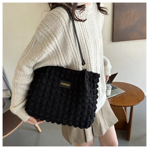 Detalle del bolso tote negro con textura de burbujas y etiqueta Fashion de moda