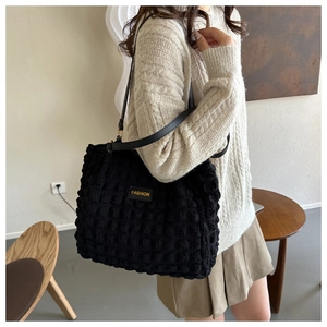 Detalle del bolso tote negro con textura plisada de burbujas y parche de piel amarillo