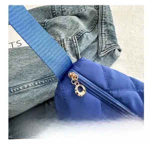 Detail of blue quilted shoulder bag with smooth golden round zipper and woven strap