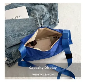Detail view showing blue quilted crossbody bag capacity with phone and wallet inside