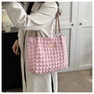 Close-up of pink pleated tote bag texture with fashion metal logo and shoulder strap