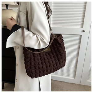 Detail of coffee brown ruched tote bag with thin leather strap and Fashion label