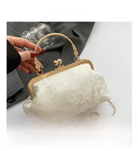 Detail of cream floral jacquard handbag with gold kiss-lock and 3D metal flower handle