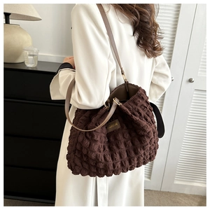 Detalle de bolso tote marrón oscuro con tejido de burbujas y etiqueta de cuero