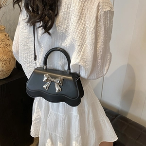 Fashionable black PU handbag with wave-shaped bottom and silver metal bow decoration