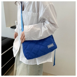 Fashionable klein blue quilted tote bag with diamond pattern and crossbody strap on model